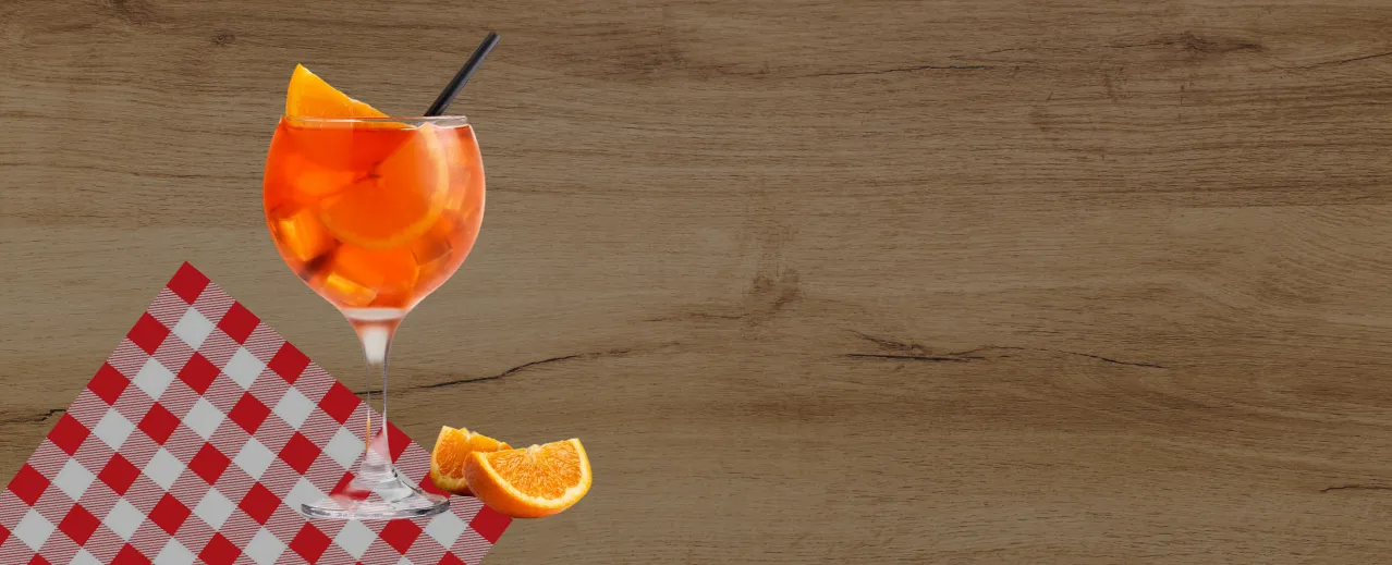 Cocktail à l’orange servi en verre ballon sur une nappe à carreaux rouges et blancs