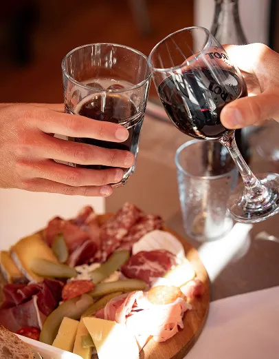 Mains servant du vin rouge et blanc avec charcuterie et fromages sur plateau