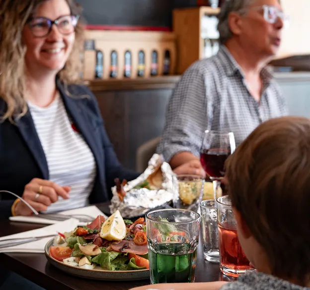 Groupe souriant partageant un repas convivial dans la brasserie-pizzeria
