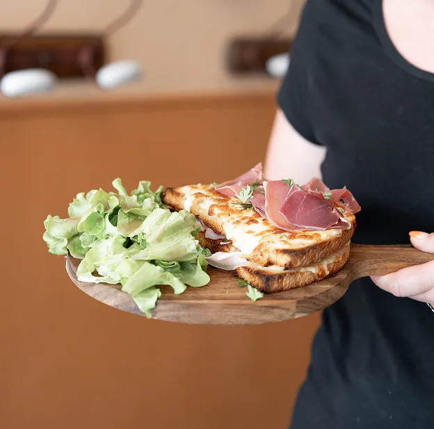 Sandwich grillé au parmesan, jambon cru et salade fraîche sur planche en bois